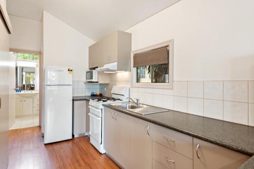 a white kitchen with a sink and a refrigerator at Discovery Parks - Lake Hume, Victoria in Bonegilla