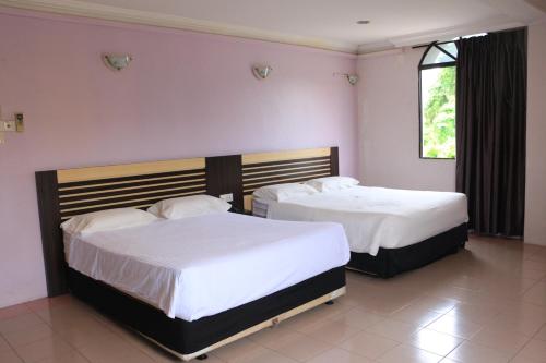 2 camas en un dormitorio con paredes rosas en Hotel Lam Seng en Pantai Remis