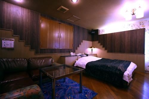 - une chambre avec un lit, un canapé et une table dans l'établissement Hotel Ohirune Racco Higashiosaka ( Adult Only), à Higashiōsaka