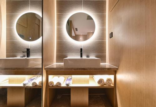 a bathroom with two sinks and two mirrors at Sincer Hotel - Temple of Heaven Beijing Tiananmen Square in Beijing