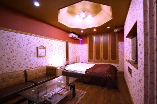 a bedroom with a bed and a couch in a room at Hotel Ohirune Racco Sakai (Adult Only ) in Sakai