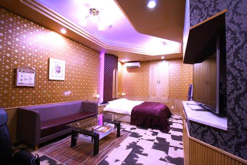 a bedroom with a bed and a couch and a tv at Hotel Ohirune Racco Sakai (Adult Only ) in Sakai