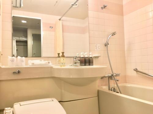 a bathroom with a toilet and a sink and a tub at Hotel Fujita Fukui in Fukui