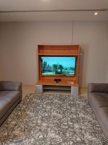 a living room with a flat screen tv and two couches at اجنحة النرجس الفندقية in Al Khobar