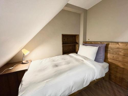 a bedroom with a large white bed and a lamp at Puli Story House in Puli