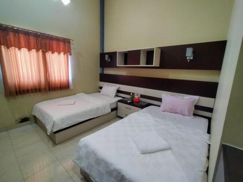um quarto de hotel com duas camas e uma janela em Hotel Pilar Mosa em Kampung Gunung Malang