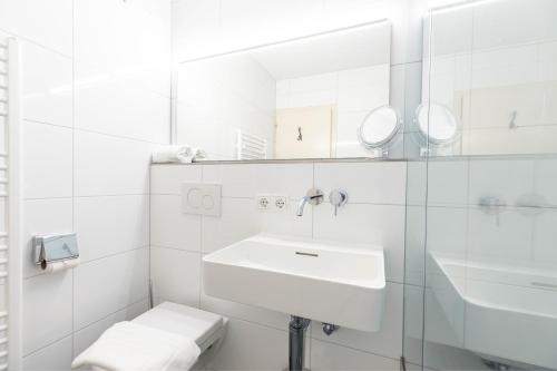 Baño blanco con lavabo y espejo en Ferienwohnung Heidi, en Schruns