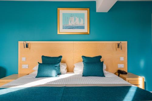 a blue bedroom with a bed with two blue pillows at Royal Maritime Hotel in Portsmouth
