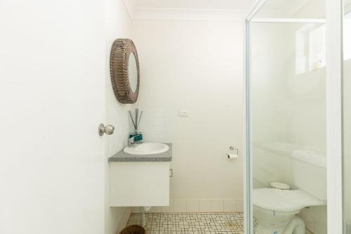 a white bathroom with a toilet and a sink at Apparition Apartments in Geraldton