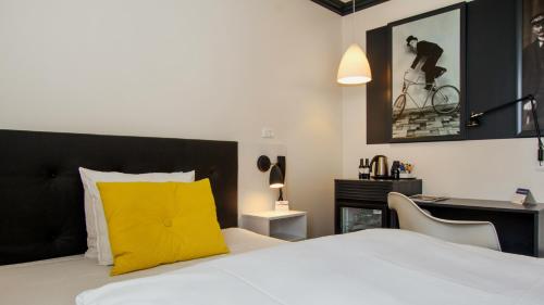 a bedroom with a bed with a yellow pillow and a desk at Best Western Plus Hotel Eyde in Herning