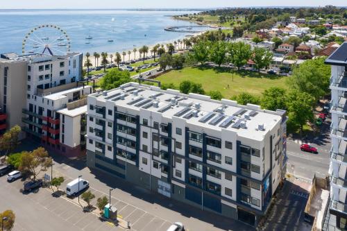 eine Luftansicht auf ein großes weißes Gebäude mit Strand in der Unterkunft Vue Apartments Geelong in Geelong