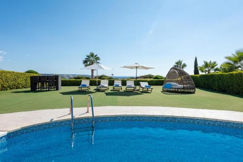 a swimming pool with chairs and umbrellas in a resort at Villa Savoya Sunrise by Ezoria Villas in Coral Bay