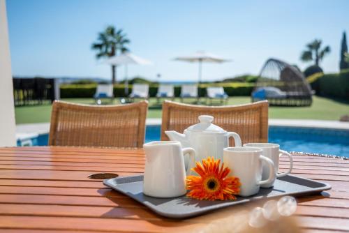 a table with a tray with cups and a flower on it at Villa Savoya Sunrise by Ezoria Villas in Coral Bay