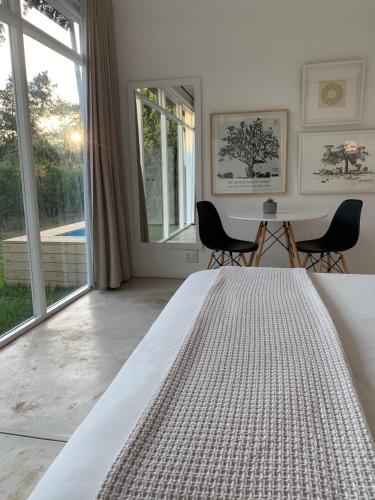 a white bedroom with a bed and a large window at Gite in Franschhoek