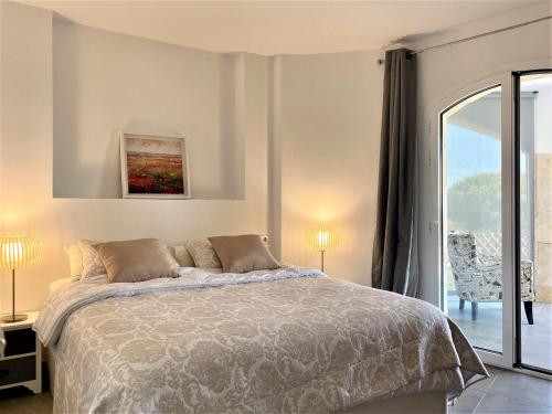 a white bedroom with a bed and a balcony at Villa Saramel con vistas panorámicas al mar in Sant Antoni de Calonge