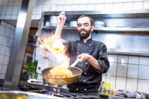 a man cooking pasta in a pan in a kitchen at Hotel Stadt Berlin in Jessen