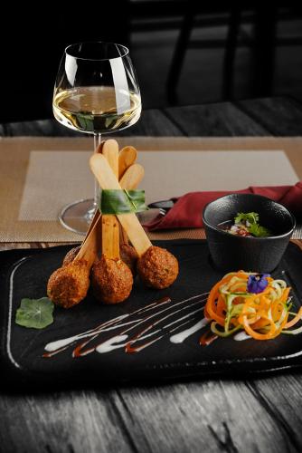 a black plate with a glass of wine and food at Dusit Thani Dubai in Dubai