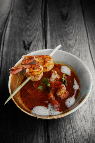 a bowl of shrimp soup on a wooden table at Dusit Thani Dubai in Dubai