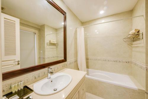 a bathroom with a sink and a tub and a mirror at City View Apartment in Phnom Penh