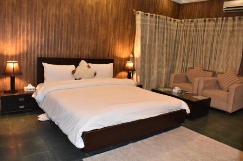 a bedroom with a large bed and a chair at Safari Club 2 Bahria Town in Rawalpindi