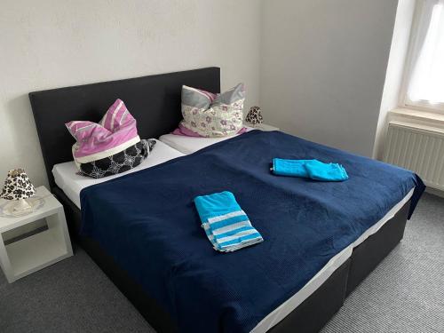 a bed with blue and pink pillows and towels on it at Ferienwohnung Etgersleben in Etgersleben