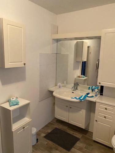a white bathroom with a sink and a mirror at Ferienwohnung Etgersleben in Etgersleben