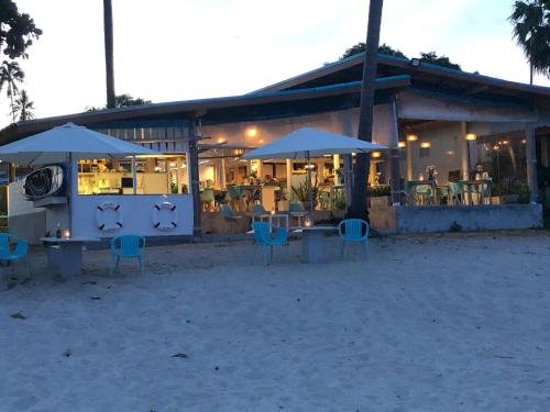 a restaurant with blue chairs and umbrellas on the beach at Le Petit Saint Tropez in Khanom