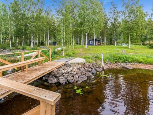 a wooden bridge over a pond with a house in the background at Holiday Home Suviranta by Interhome in Suonenjoki