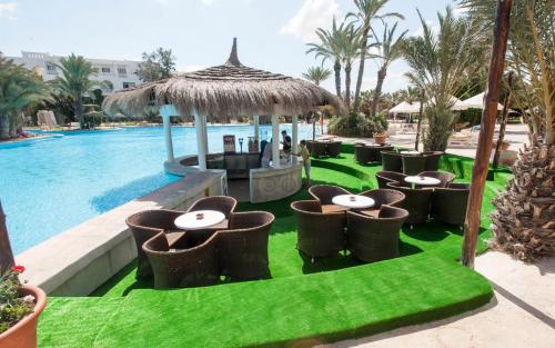 Djerba Resort- Families and Couples Only في حومة السوق: مجموعة طاولات وكراسي بجانب مسبح