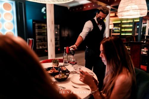 a man pouring a glass of wine at a table with a woman at Dusit Thani Dubai in Dubai