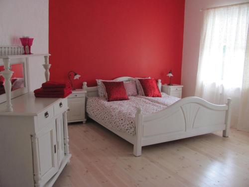 a bedroom with a white bed and a red wall at Heimdallhuset in Skånes Värsjö