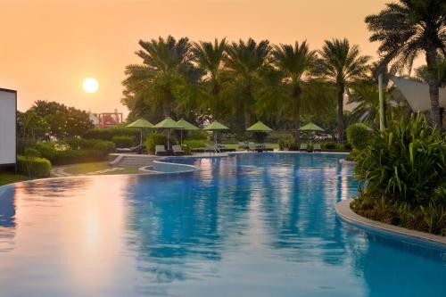 a large swimming pool with palm trees and umbrellas at Mövenpick Hotel Bahrain in Manama