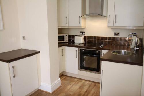 a kitchen with white cabinets and a sink at Mostyn Villa 2 Free Private Parking in Llandudno