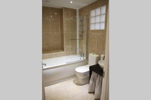 a bathroom with a tub and a toilet and a sink at Mostyn Villa 2 Free Private Parking in Llandudno