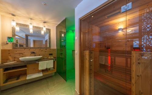 La salle de bains est pourvue d'un lavabo et d'une douche avec un miroir. dans l'établissement Hotel Weiher Green Lake, à Falzes