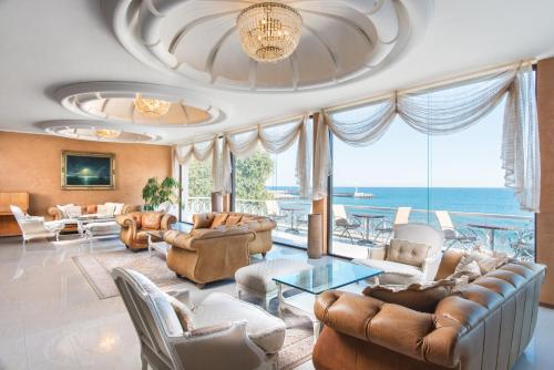 a living room with couches and chairs and the ocean at The Palace Hotel, Sunny Day in Saints Constantine and Helena