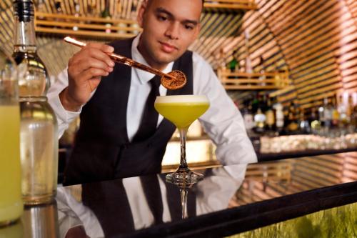 a man stirring a drink with a stick in a cocktail at Mövenpick Hotel Bahrain in Manama