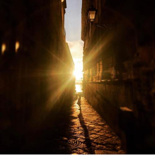 an alley with the sun setting in the distance at La Residenza del Reginale in Siracusa