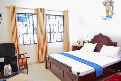 a bedroom with a bed and a tv and windows at TEVAH SUITES in Mombasa