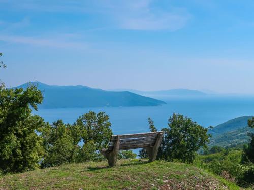 a bench on a hill with a view of a lake at Holiday Home Elija by Interhome in Mošćenička Draga