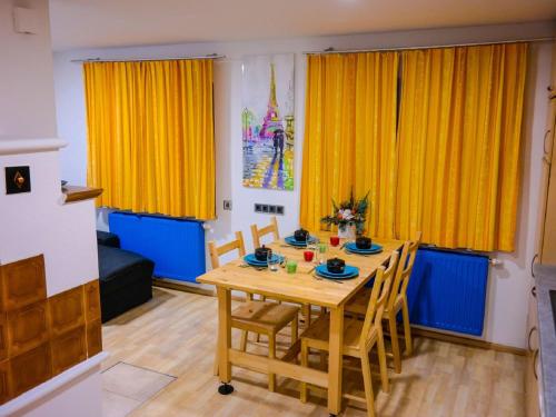 jadalnia z drewnianym stołem i żółtymi zasłonami w obiekcie Apartment Dachsteingasse by Interhome w Schladming