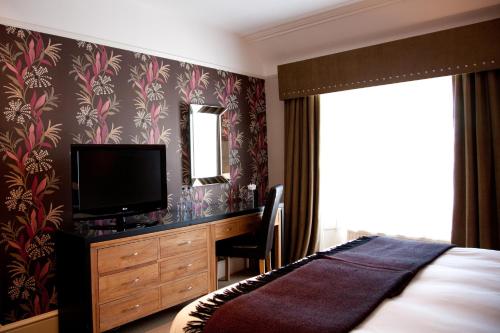 a bedroom with a bed and a desk with a television at The Townhouse Hotel in Melrose