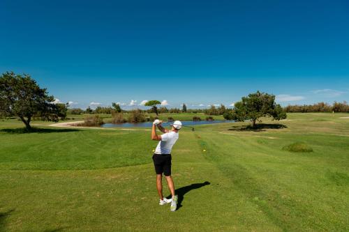 a man swinging a golf club on a golf course at Isola di Albarella Golf Hotel in Isola Albarella