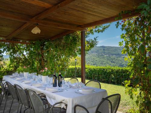 a table under a pergola with wine bottles and glasses at Holiday Home La Vittoria by Interhome in Poggioni