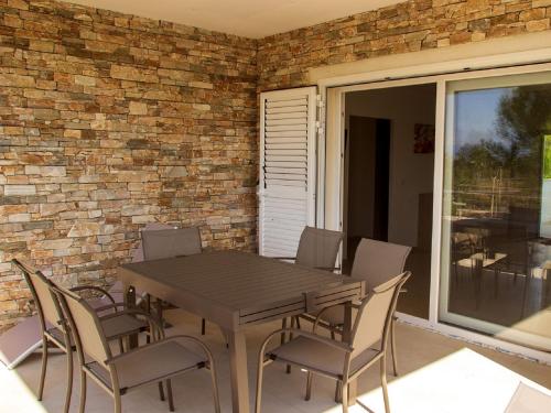 a wooden table and chairs in front of a brick wall at Apartment A Suara Linda-2 by Interhome in Ghisonaccia