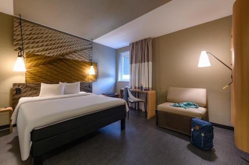 a hotel room with a large bed and a chair at ibis Zürich City West in Zurich