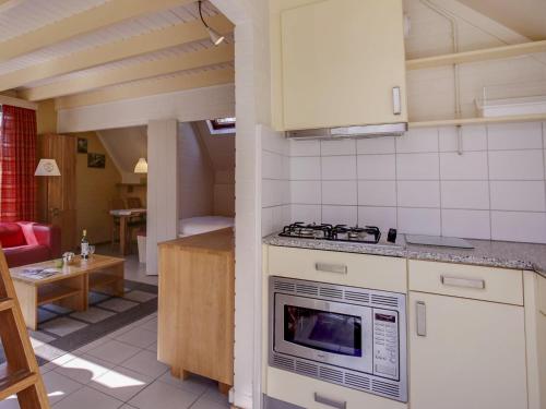 a kitchen with a stove top oven next to a living room at Holiday Home 4-persoons by Interhome in Dalfsen
