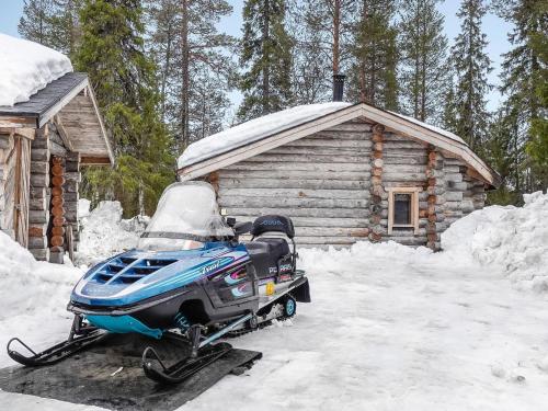 una moto de nieve estacionada frente a una cabaña de madera en Holiday Home Kelokota by Interhome en Salla