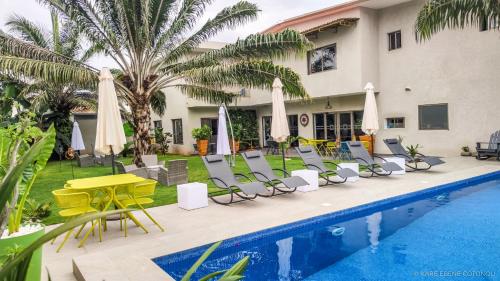 a hotel with a pool and chairs and umbrellas at Le Karé Ébène in Cotonou