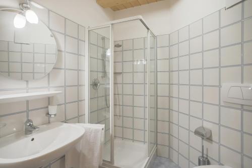 uma casa de banho com um chuveiro, um lavatório e um espelho. em Appartements Eppanerhof em Appiano sulla Strada del Vino